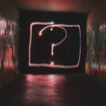 A dark hallway with a large glowing question mark on the wall at the end.