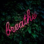the word breathe in pink neon text