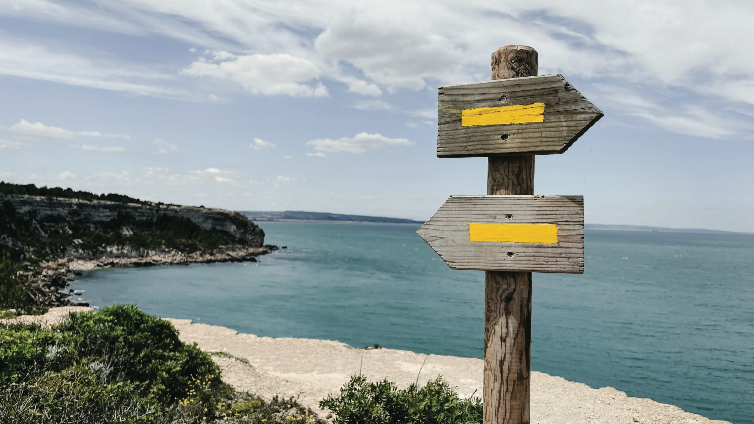 Two signs, one pointing right and one pointing left, on the beach.