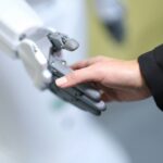 human hand holding a robot hand as if in a handshake
